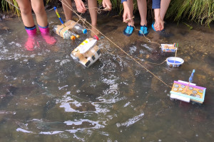 Kinder mit Booten am Bach