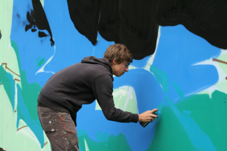 Grafitti Sprayer bei Fluss mit Flair