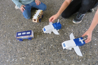 Kinder spielen mit selbst gebauten Fahrzeugen