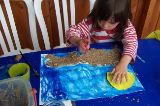 Kind beim Gestalten eines Sandbildes