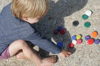 Kind spielt mit alten Plastikdeckeln
